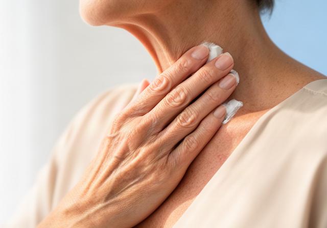 Mujer madura aplicando crema con movimientos ascendentes en cuello y escote